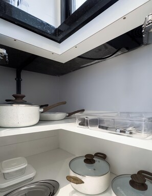 Una cocina con armarios blancos, una olla sobre la encimera y un ventanal.