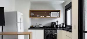 Una cocina compacta con refrigerador, microondas, cafetera y lavavajillas.