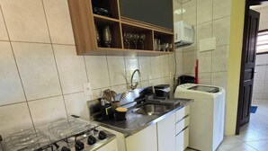 A compact kitchen with a gas stove, a microwave, and a sink. - Casa Lagostina 02, Bombinhas Center, 600 meters from the beach. (Bombinhas)