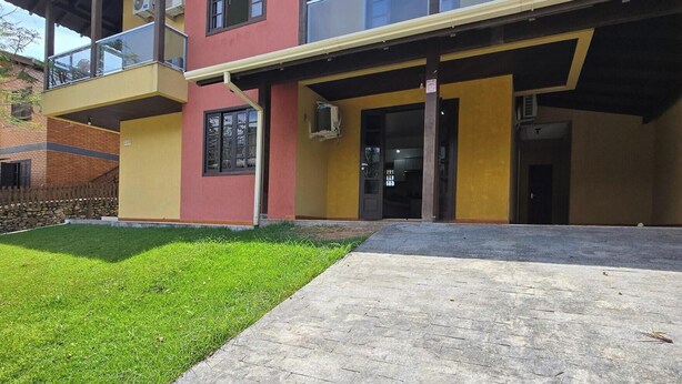 A multi-story building with a flat roof, a balcony, and a paved entrance area. - Casa Lagostina 02, Bombinhas Center, 600 meters from the beach. (Bombinhas)