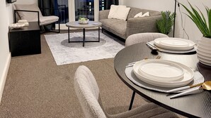 Una sala de estar moderna con un sofá, una mesa de centro y un comedor dispuesto con platos y cubiertos.
