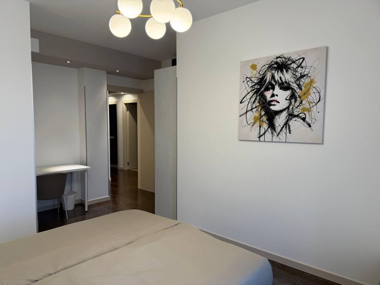 Une chambre moderne équipée d’un lit, d’un bureau et d’une œuvre d’art accrochée au mur.