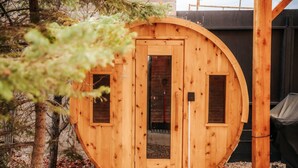 Eine finnische Holzsauna mit kreisrunder Form, einer Tür und zwei Fenstern.