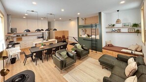 Eine moderne Wohnung mit Küche, Essbereich und Wohnzimmer mit Sofas und einem Bett.