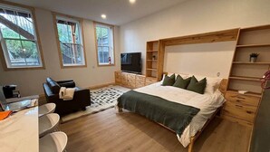 Ein Schlafzimmer mit Bett, Fernseher, Schreibtisch und Stuhl.