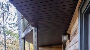 Una terraza de madera con una mesa y sillas, con vistas a un área boscosa.