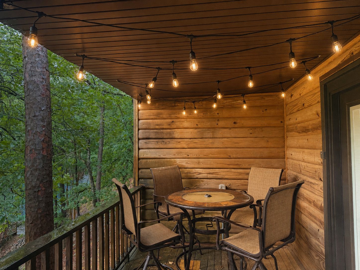 A wooden cabin with a round table and four chairs, surrounded by a wooden deck and a wooden wall.