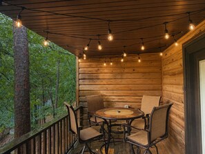 Eine Holzhütte mit einem runden Tisch und vier Stühlen, umgeben von einer Holzterrasse und einer Holzwand.