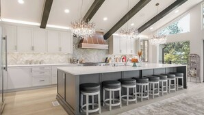 Una cocina moderna con una isla grande, taburetes de bar e iluminación colgante.