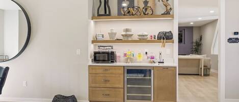 A modern kitchen with wooden cabinets, a microwave, and a built-in oven. There are decorative items on the shelves, including a sign that says "King" and "Queen."