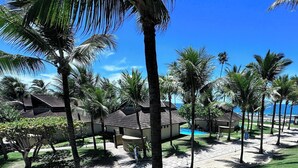 A resort with a swimming pool, palm trees, and a clear blue sky. - Marulhos Suítes Resort (Ipojuca)