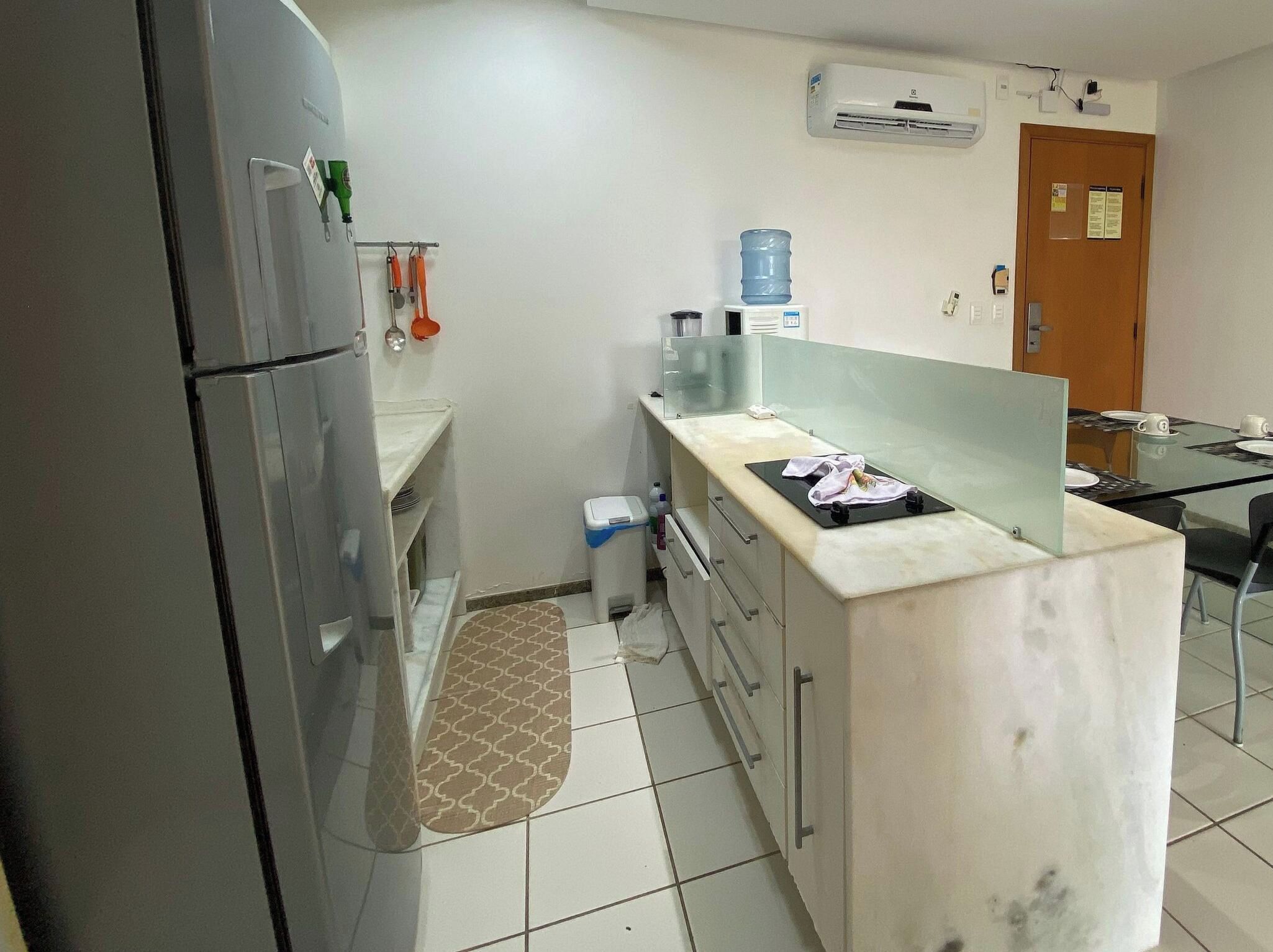 Uma cozinha com geladeira, bebedouro, pia e bancada.
