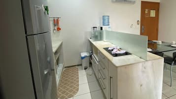 Uma cozinha com geladeira, bebedouro, pia e bancada.