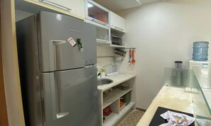 A compact kitchen with a stainless steel refrigerator, a sink, and a countertop with a water dispenser. - Marulhos Suítes Resort (Ipojuca)