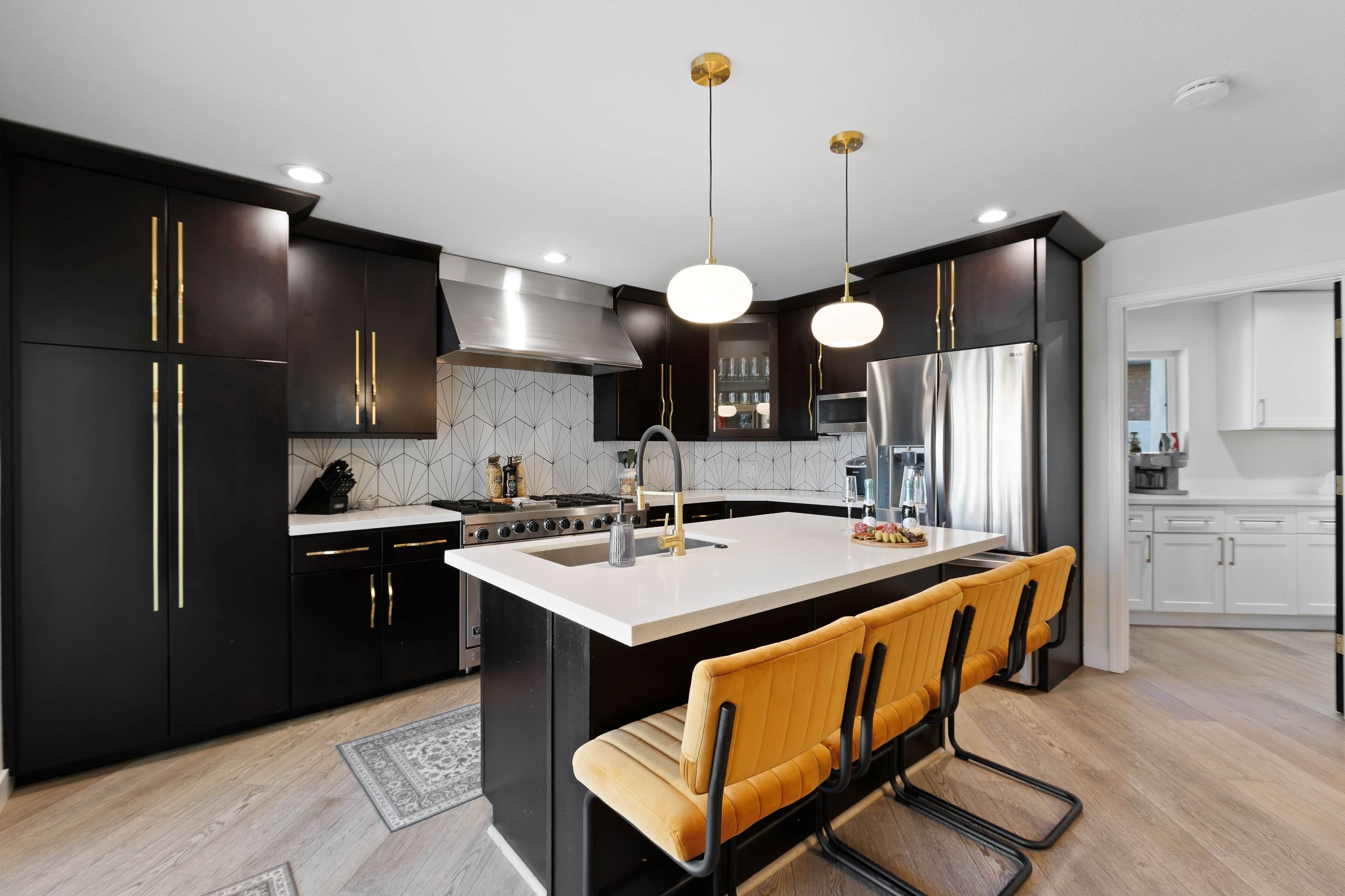 Une cuisine moderne avec des meubles de couleur noire, un îlot central et un coin bar.