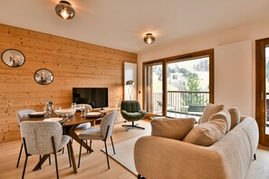 Una sala de estar moderna con una pared de madera, un comedor con mesa preparada para cuatro personas y un ventanal con vistas al exterior.