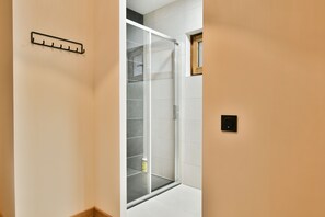 Un bagno moderno con box doccia in vetro, porta asciugamani e una piccola finestra.