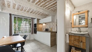 Une cuisine moderne avec des meubles blancs, une table à manger en bois et une grande fenêtre.