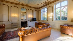 Un salon luxueux avec un grand canapé capitonné, une cheminée et un téléviseur.