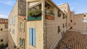 A building with a tiled roof, multiple windows with shutters, and a balcony with plants. - L'Azur Antibois – Charme & confort dans le Vieil Antibes (Antibes)