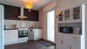 Een moderne keuken met witte kastjes, een magnetron en een fornuis.