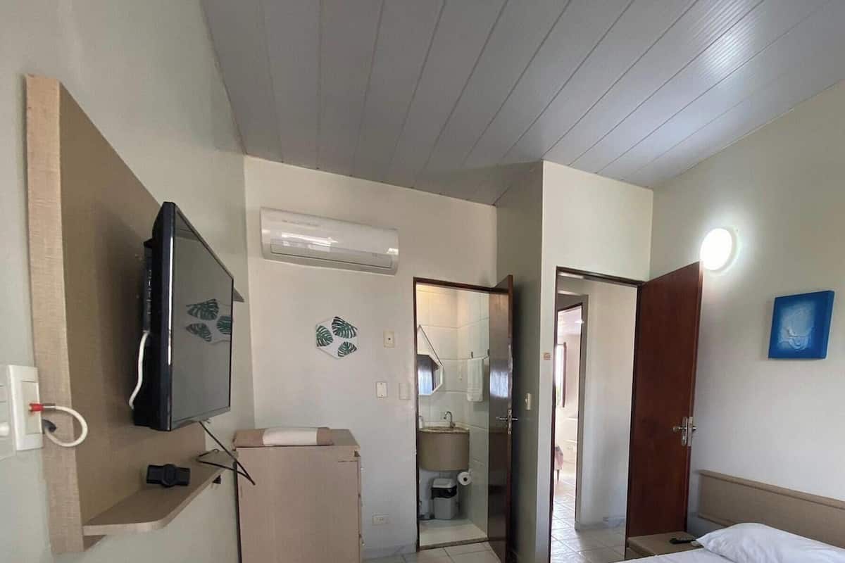 Habitació d'hotel amb un llit, una televisió, un bany i una porta que dona a una altra habitació.