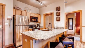 Eine moderne Küche mit einem Edelstahl-Kühlschrank, Holzschränken, einer Granit Arbeitsplatte und einem Einbauofen.