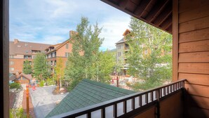 Blick von einem Balkon auf einen Innenhof mit Gebäuden, Bäumen und einem begrünten Bauwerk.
