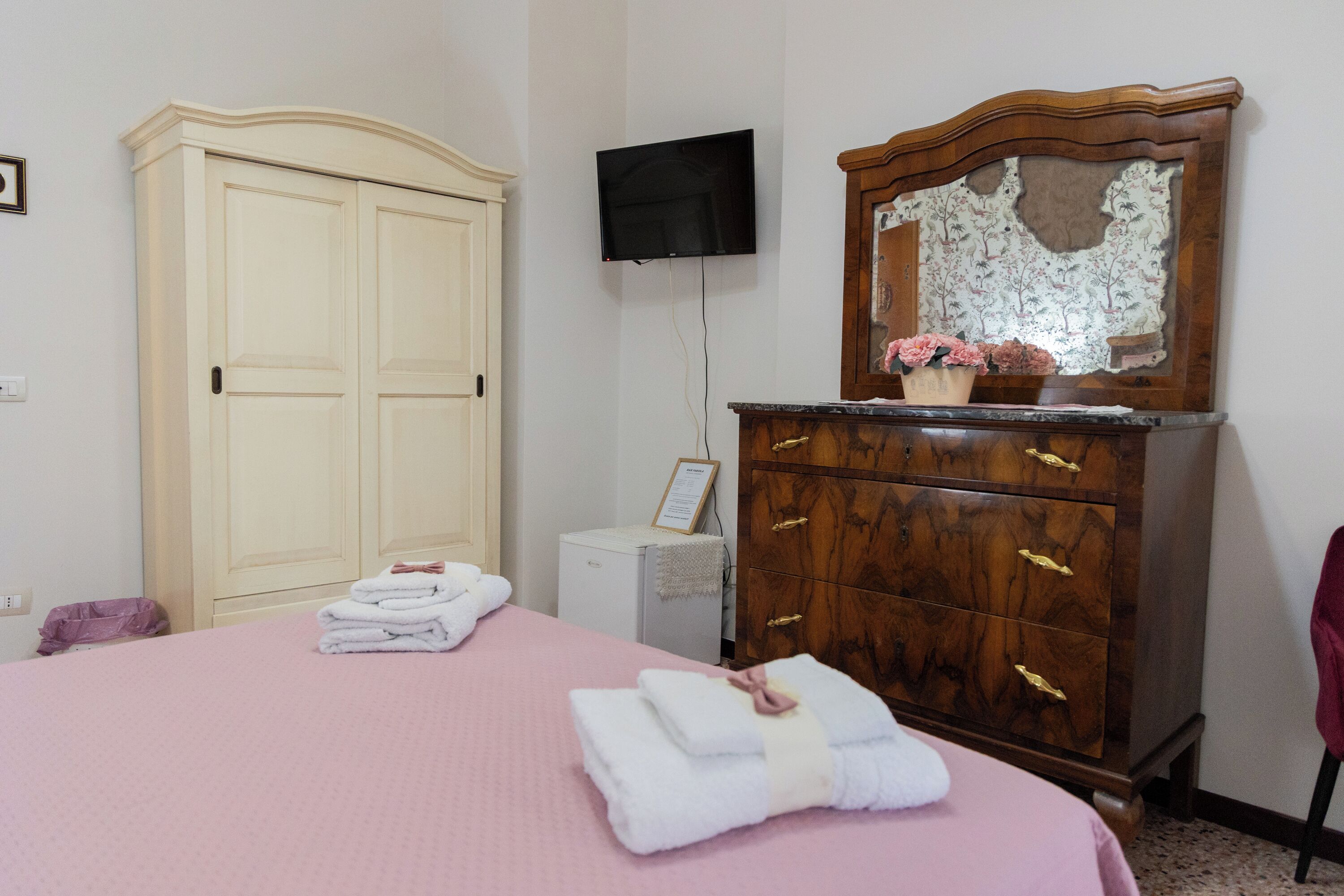 A bedroom with a bed, a wardrobe, a television, and a dresser.