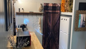 A compact kitchen with a wooden countertop, a white refrigerator, and a rustic door.