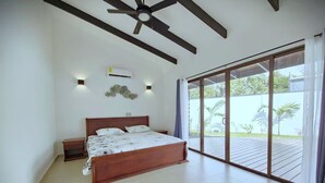 Un dormitorio con una cama grande, un ventilador de techo y un ventanal corredera que da a un balcón.