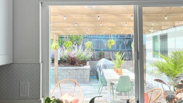 Eine moderne Küche mit großem Fenster, Spüle und hängenden Pflanzen.