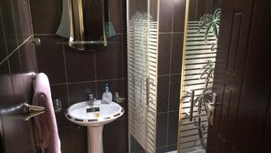 Een badkamer met een witte wastafel, een douchecabine van glas en een handdoekrek.