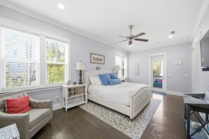 A bedroom with a bed, nightstands, a chair, a ceiling fan, and a view of the outside. - 30A Escape,  close to Beach Access and Epic Pool (Santa Rosa Beach)