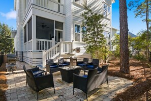 A white two-story house with a balcony, outdoor seating area with wicker furniture, and a barbecue grill. - 30A Escape,  close to Beach Access and Epic Pool (Santa Rosa Beach)