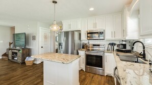 Una cocina moderna con armarios blancos, electrodomésticos de acero inoxidable y una isla central.