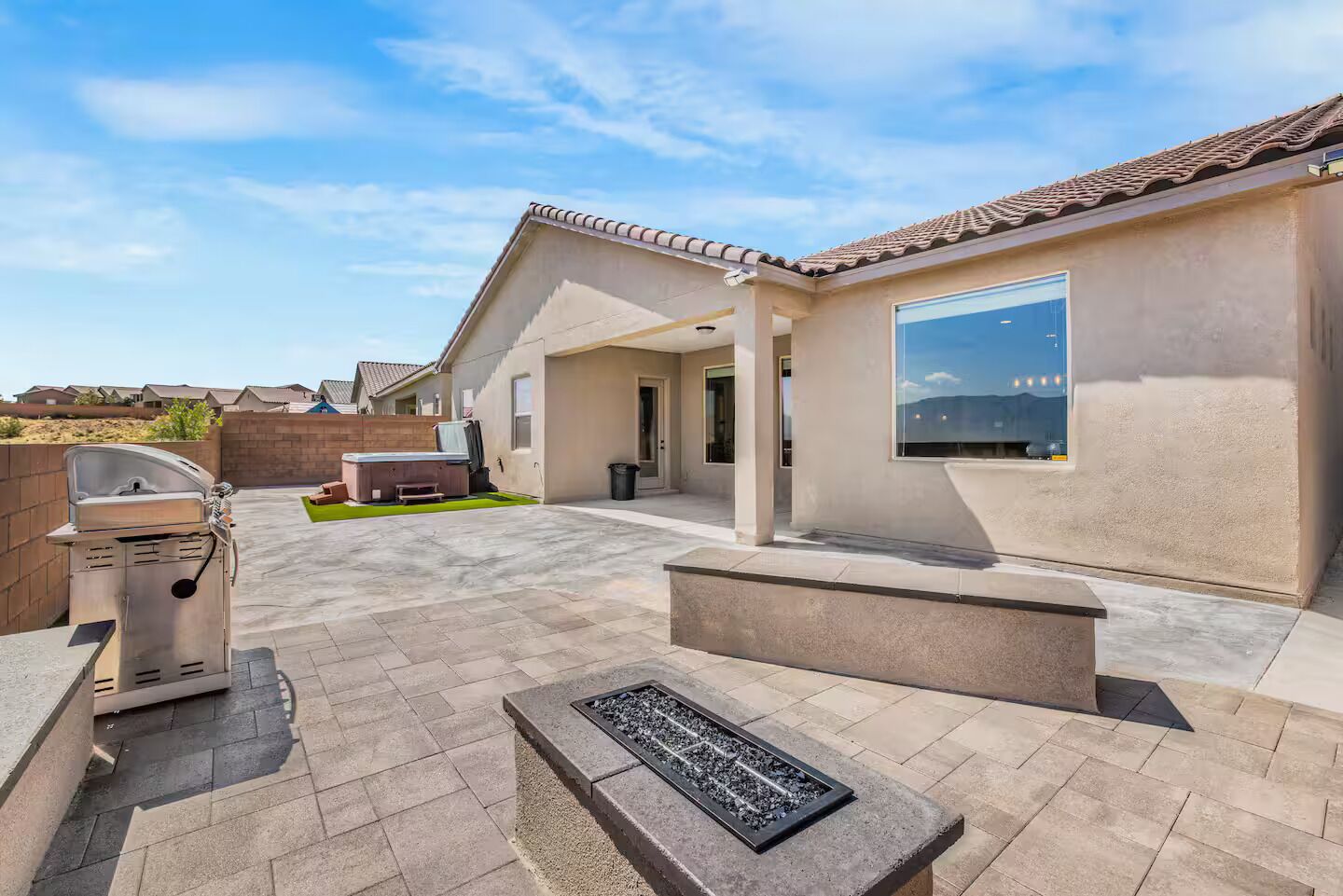A modern outdoor patio with a grill, seating area, and a fire feature.