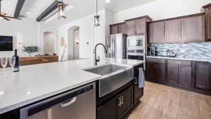 A modern kitchen with stainless steel appliances, a large island, and dark wood cabinets. - 4-bedroom + Hot tub + Firepit + Sandia views (Rio Rancho)
