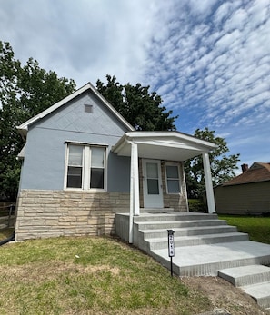 A residential house with a stone foundation, a front porch, and a small set of concrete steps leading to the front door. - Comfy, Quiet, Clean & Affordable! Great Location! Best bang for your buck! (Granite City)