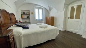 A bedroom with a wooden bed, a wardrobe, a bookshelf, and a window with curtains. - Ancient House by Wonderful Italy  (Sanremo)