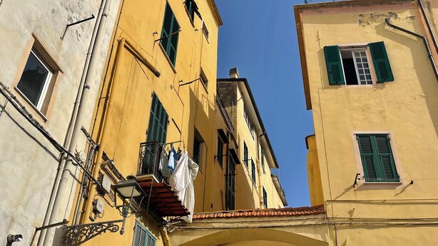 A narrow street with yellow buildings, a sign reading "Piazza San Siro," and laundry hanging on a balcony. - Ancient House by Wonderful Italy  (Sanremo)
