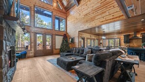A spacious living area with a fireplace, large windows, and a cozy seating arrangement. - Spacious 5-bedroom cabin Centrally located in Hochatown with Backup Generator (Broken Bow)
