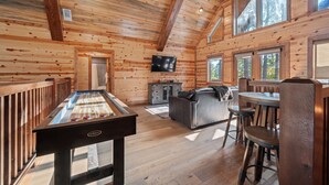A wooden interior with a pool table, a sofa, and a TV mounted on the wall. - Spacious 5-bedroom cabin Centrally located in Hochatown with Backup Generator (Broken Bow)