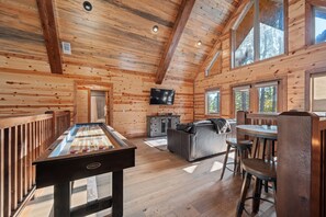 Ein Holzinterieur mit Pooltisch, einer Couch und einem an der Wand befestigten Fernseher.
