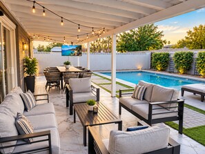 An outdoor patio with a pool, seating area, and string lights. - Pool | Game Yard · Old Town Views (Scottsdale)