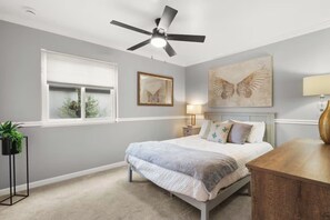A bedroom with a bed, a ceiling fan, a bedside table, a lamp, and a window with blinds. - Pool | Game Yard · Old Town Views (Scottsdale)