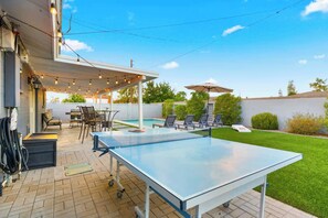 A pool table in a backyard with a covered patio area, outdoor seating, and a hose reel. - Pool | Game Yard · Old Town Views (Scottsdale)