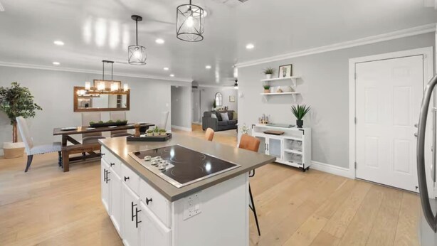 Cozinha espaçosa com ilha central, iluminação pendente e área de refeições com mesa e cadeiras modernas.
