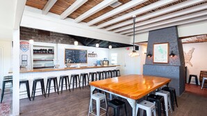 A bar area with a long wooden counter, black stools, and a chalkboard menu. - Bright Modern Home in Central Phx w/ Private Yard 8min to Airport & Downtown (Phoenix)