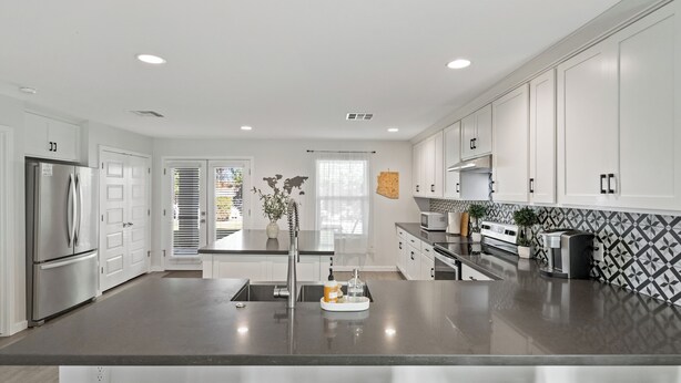 A modern kitchen with white cabinets, a central island, and stainless steel appliances. - Bright Modern Home in Central Phx w/ Private Yard 8min to Airport & Downtown (Phoenix)